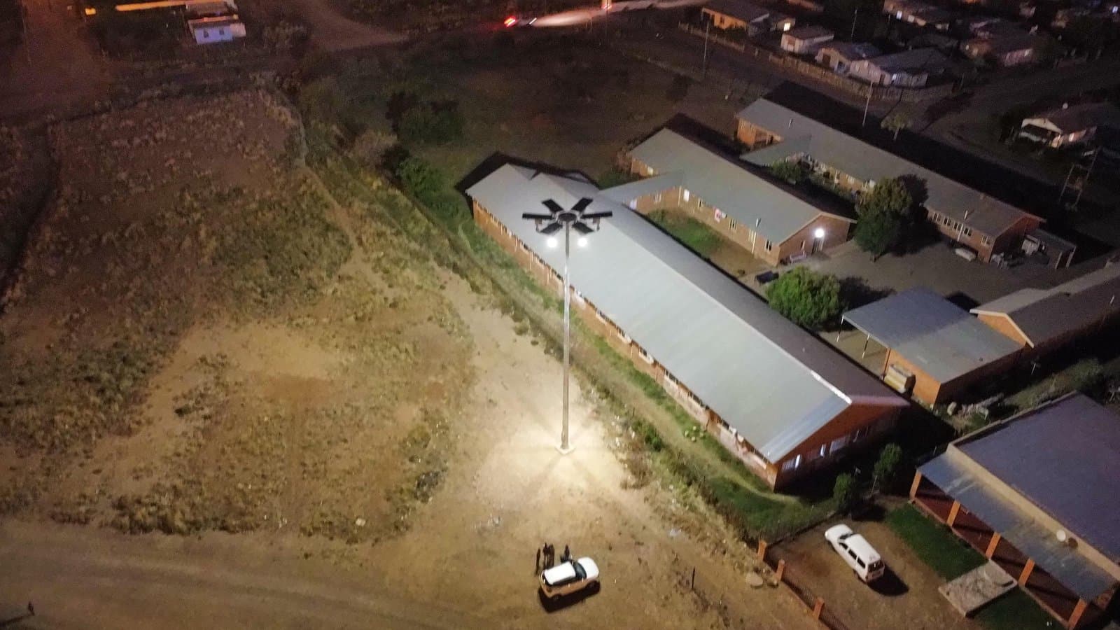 Aerial view at night of a Quebar-installed high mast flooding a community facility and its grounds with light in Prieska